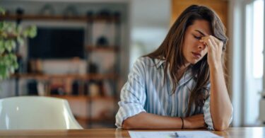 A mother sitting at a table with legal documents and feeling stressed about her upcoming child custody case.