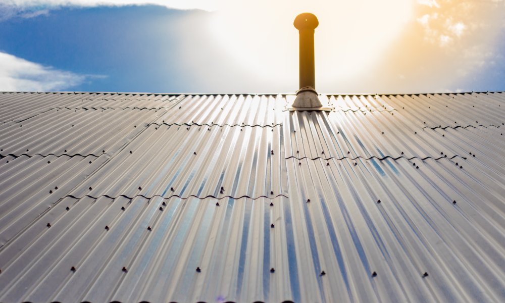 Aluminum panels drilled onto the roof of a building. There is a roof pole sticking out from the metal panels on the roof.