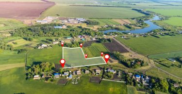 Aerial view of a large area of land with green, lush grass and digital lines and pins delimiting a smaller area.