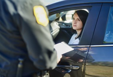 A woman and a traffic officer, who has issued a ticket, are at a security and crime investigation checkpoint on the highway.