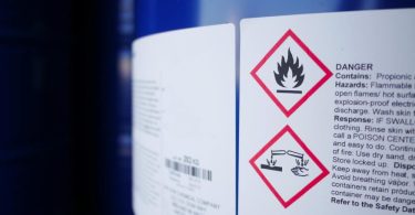 The warning label on the side of a blue tank. The warnings include a flammable warning and a corrosive warning.