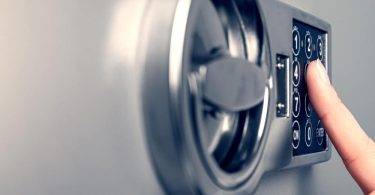 A close-up of someone's hand pressing the numbers on the stainless steel safe as they unlock or lock the safe.