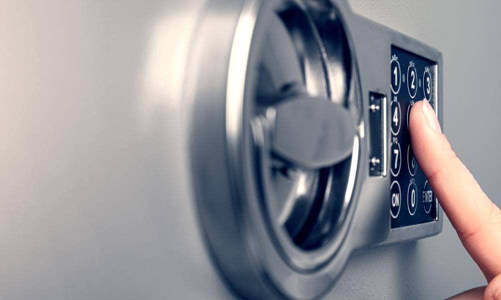 A close-up of someone's hand pressing the numbers on the stainless steel safe as they unlock or lock the safe.