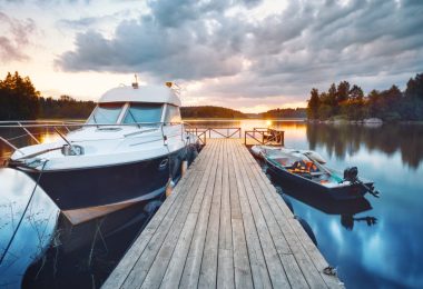 A wooden dock is sitting on the water. There is a large boat to the left of frame and a smaller one to the right.