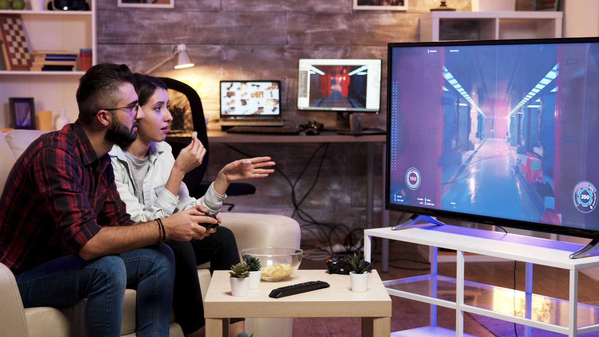 Man playing video games on TV while sitting on couch with girlfriend nearby