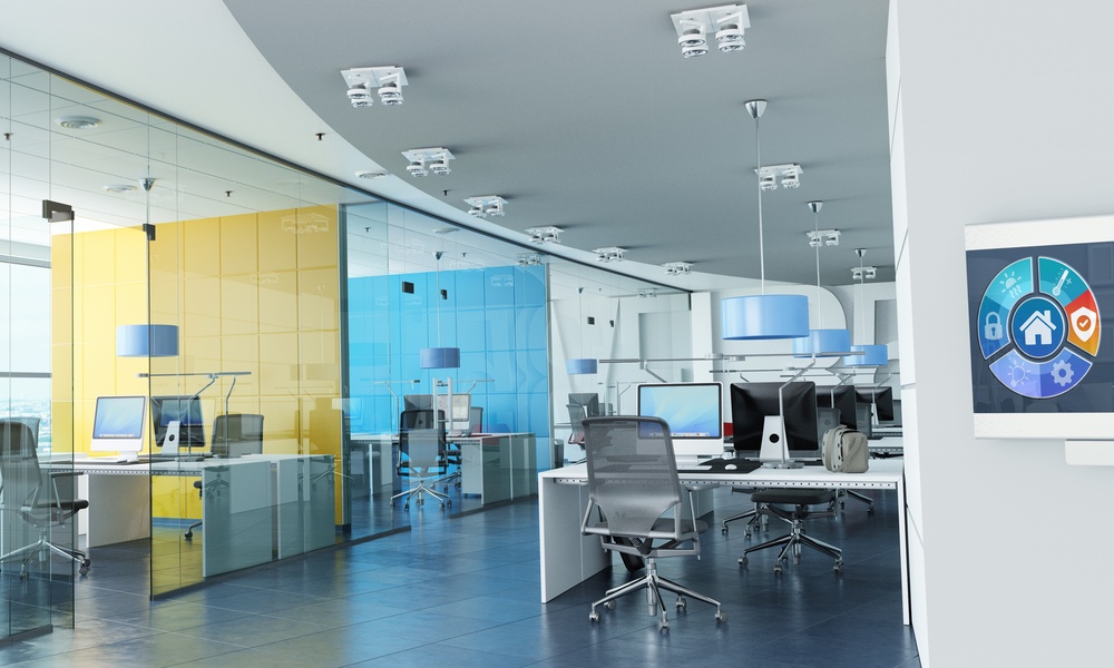 A close-up on a control panel on the wall leading into an office space with several desks and room spaces.