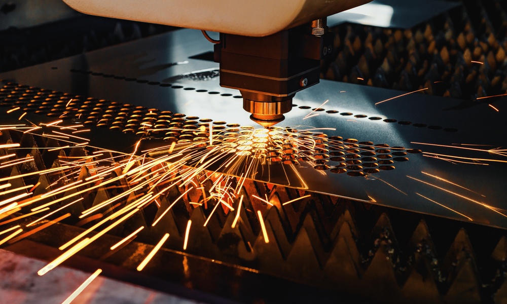 A high-precision CNC machine uses a laser to cut holes in a metal sheet. It creates sparks as it works.