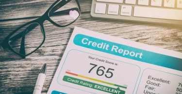 A piece of paper that says credit report on it along with the number 765 next to pair of glasses and a keyboard.