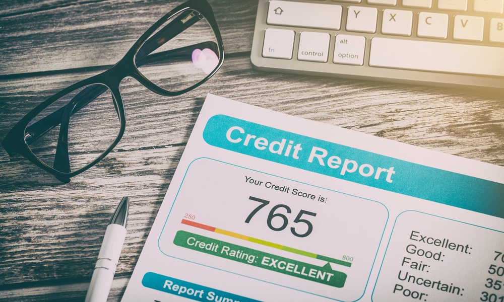 A piece of paper that says credit report on it along with the number 765 next to pair of glasses and a keyboard.
