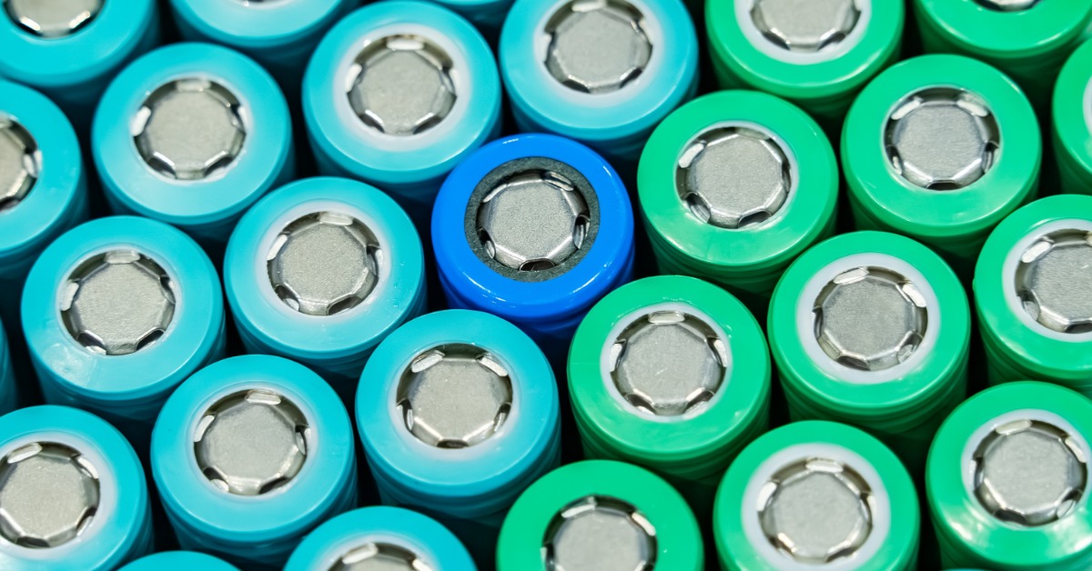 Rows of blue, turquoise, and green cylindrical battery cells arranged closely together, each with a silver metal top.