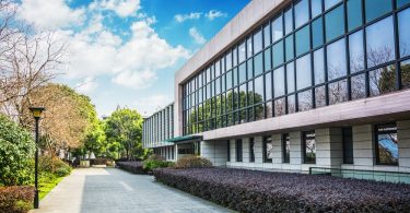 The exterior of a commercial property with freshly groomed landscaping and clean sidewalks. There are a lot of windows.