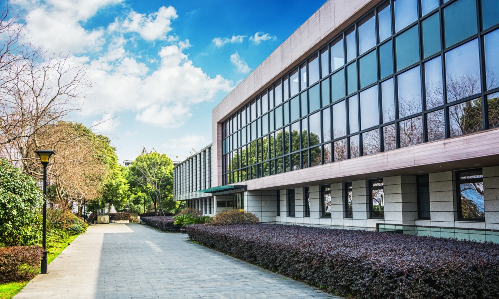 The exterior of a commercial property with freshly groomed landscaping and clean sidewalks. There are a lot of windows.