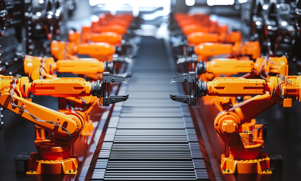 A view looking down the assembly line of a modern factory with the line flanked by numerous stationary robotic arms.
