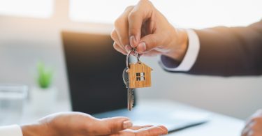 One person is holding out a pair of keys and another person is extending their hand to take the keys.