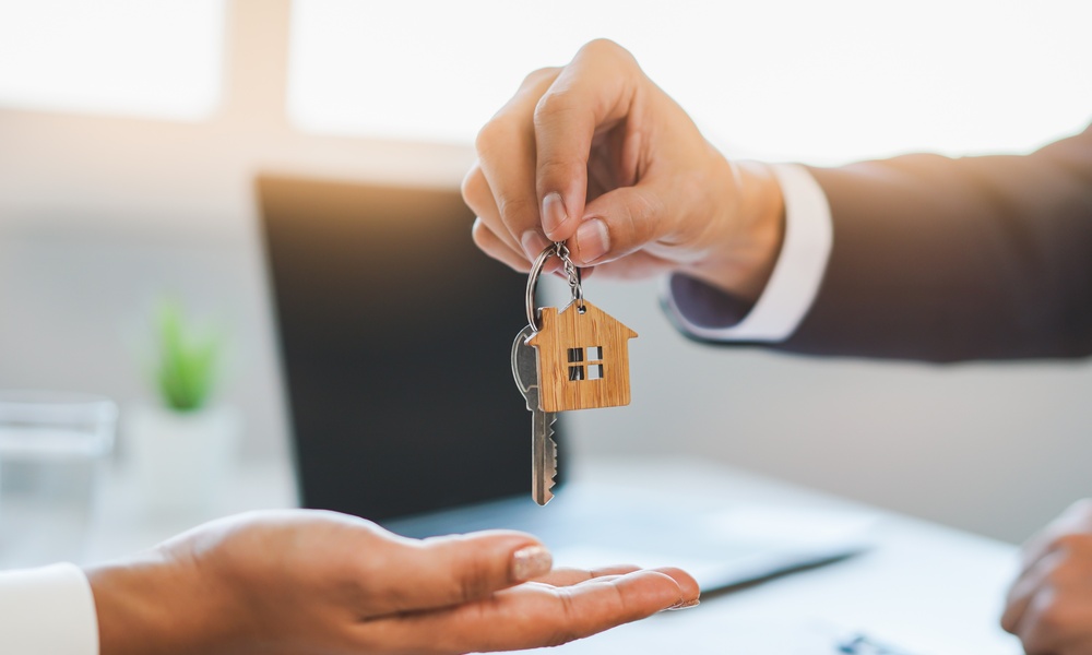 One person is holding out a pair of keys and another person is extending their hand to take the keys.